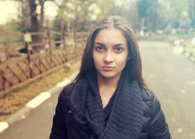 Young woman in a cozy scarf poses confidently in an autumn park.